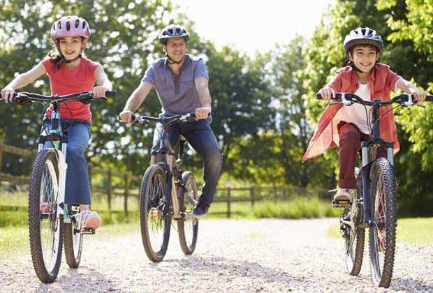 Une famille de trois en vélo dans un parc