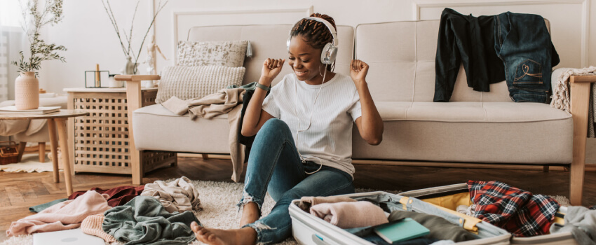 Femme avec casque d'écouteur joyeuse qui range son bagage