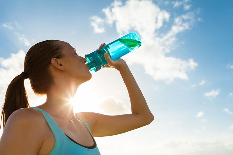 femme buvant de l'eau au soleil