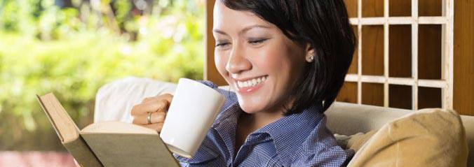 Une madame lit un livre en buvant d'une tasse