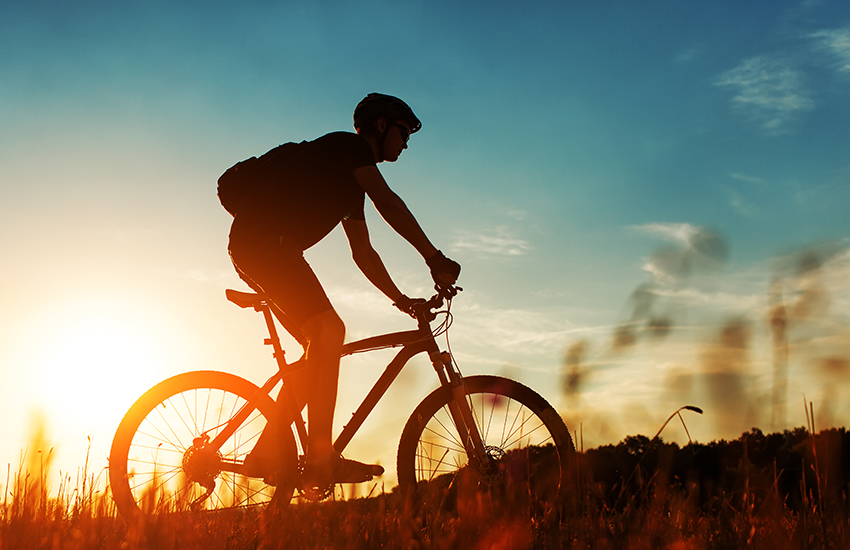 Un homme en vélo devant le soleil