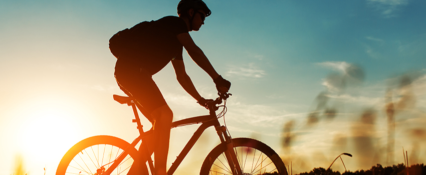 Un homme en vélo devant le soleil