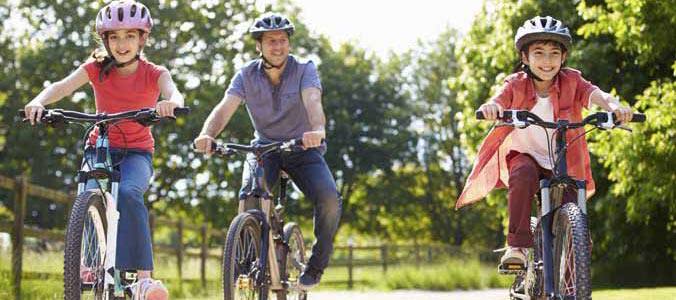 Une famille de trois en vélo dans un parc