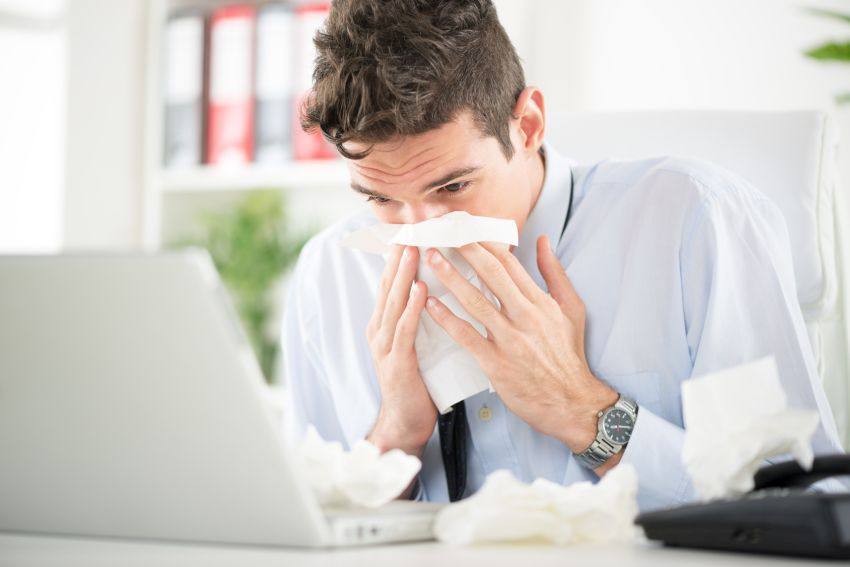 Un homme se mouche devant son ordinateur